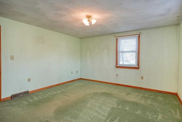 carpeted empty room with baseboards, a textured ceiling, and visible vents