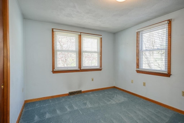 carpeted spare room featuring a textured ceiling, visible vents, and baseboards
