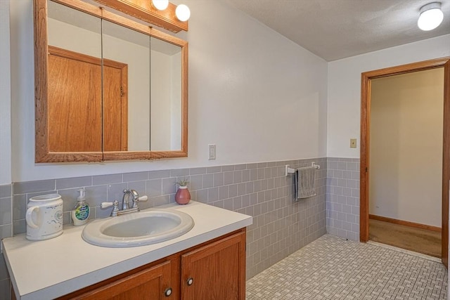 bathroom with vanity, wainscoting, and tile walls