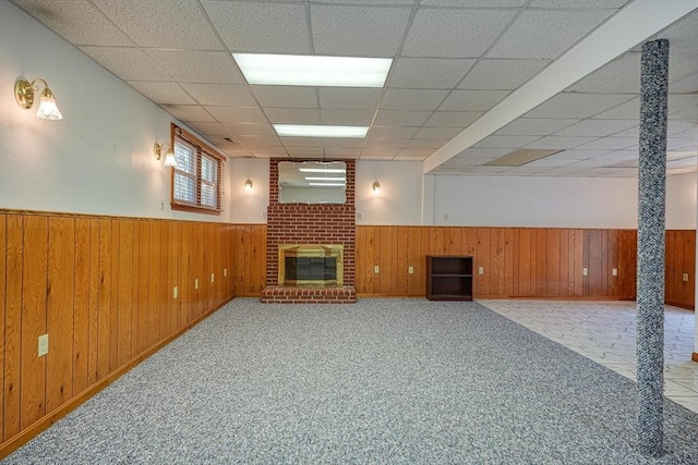 below grade area featuring wooden walls, a fireplace, and a wainscoted wall