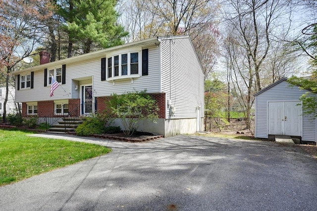 split foyer home with a storage unit, brick siding, an outbuilding, a chimney, and driveway