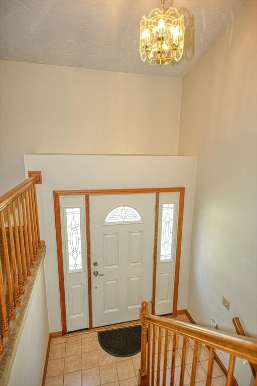 foyer entrance featuring light tile patterned floors, baseboards, stairs, and a notable chandelier