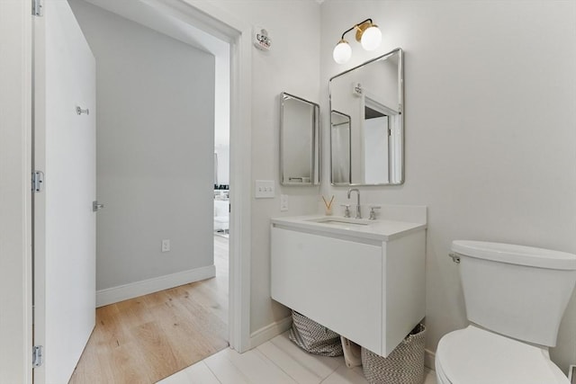 191 Washington St Unit 524, Boston, MA 02135 - bathroom featuring vanity, toilet, baseboards, and wood finished floors