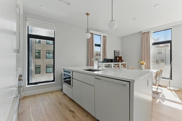 191 Washington St Unit 524, Boston, MA 02135 - kitchen with a sink, dishwashing machine, light wood finished floors, light countertops, and white cabinetry