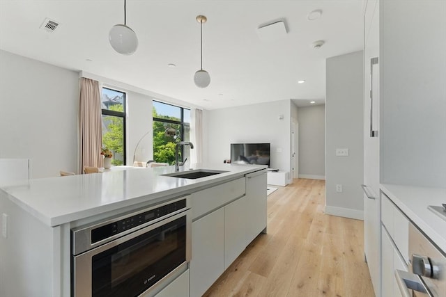 191 Washington St Unit 524, Boston, MA 02135 - kitchen with a sink, wall oven, open floor plan, light countertops, and light wood finished floors