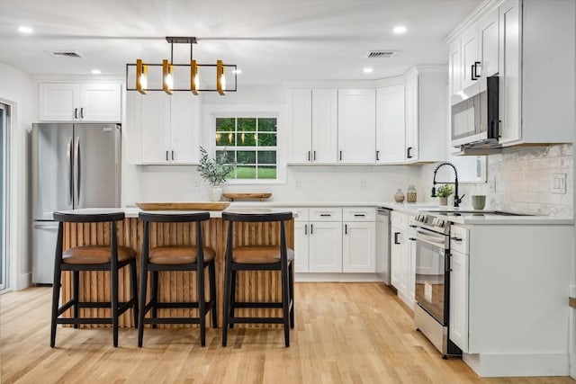 22 Longhill Rd, Ashland, MA 01721 - kitchen with stainless steel appliances, a kitchen bar, white cabinets, light wood-type flooring, and recessed lighting