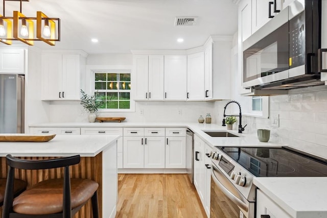22 Longhill Rd, Ashland, MA 01721 - kitchen with appliances with stainless steel finishes, a sink, light wood-type flooring, backsplash, and white cabinetry