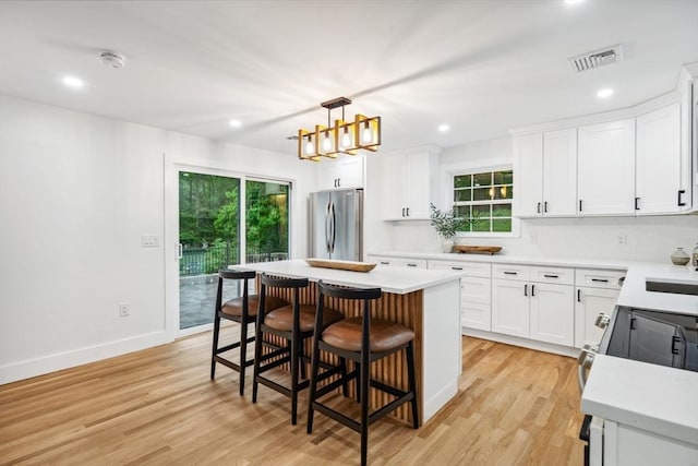 22 Longhill Rd, Ashland, MA 01721 - kitchen with freestanding refrigerator, a breakfast bar area, light wood-style floors, light countertops, and white cabinetry