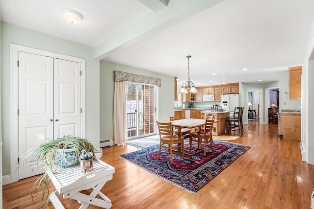 dining space featuring a chandelier, beam ceiling, baseboard heating, and light wood-style flooring