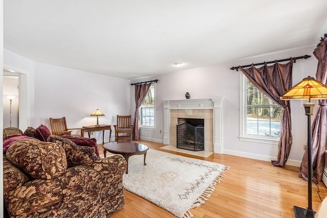 living area with light wood finished floors, a fireplace, and baseboards