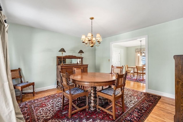 dining area with a notable chandelier, baseboards, and wood finished floors