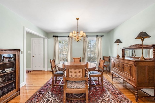 dining room with light wood-style flooring, a chandelier, and baseboards