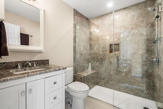 bathroom featuring toilet, a stall shower, and vanity