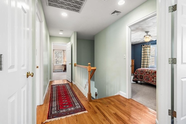 hall featuring visible vents, an upstairs landing, and a healthy amount of sunlight