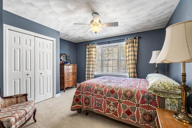 carpeted bedroom with a ceiling fan, a closet, and a textured ceiling