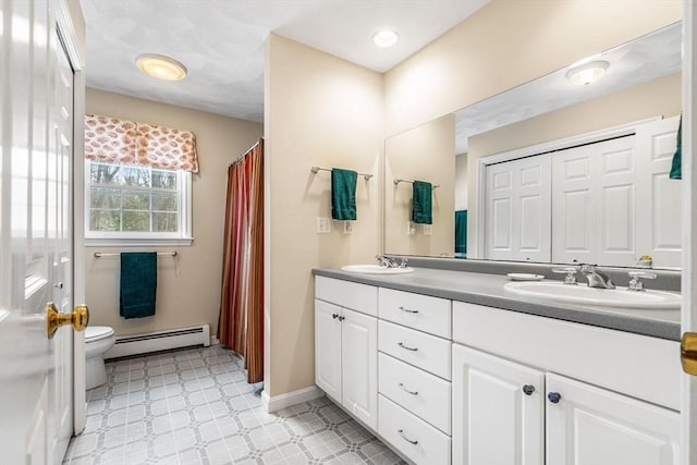 full bath featuring a baseboard radiator, a sink, toilet, and double vanity