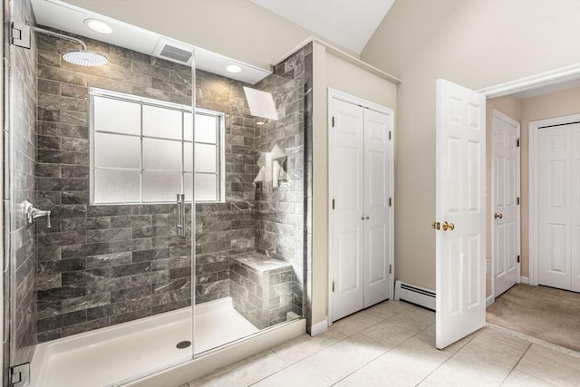 full bathroom featuring a closet, visible vents, a baseboard heating unit, a stall shower, and tile patterned flooring