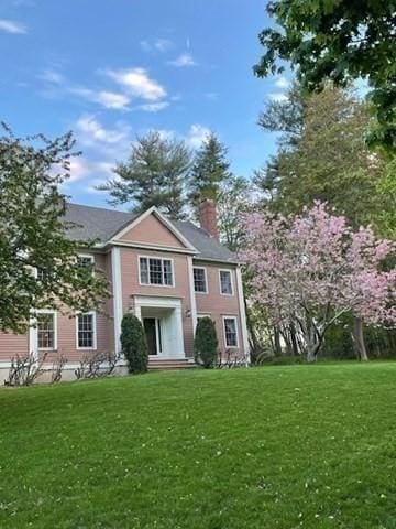 view of front facade with a chimney and a front yard