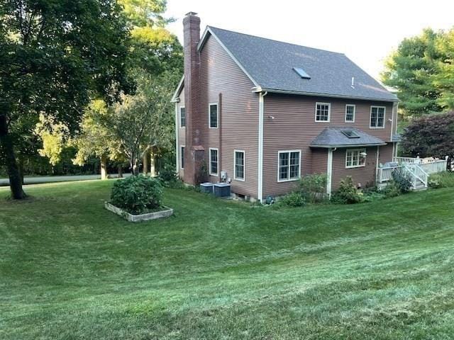 rear view of house featuring a lawn and a chimney