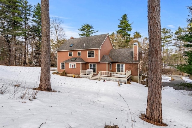 snow covered property with a chimney and a deck