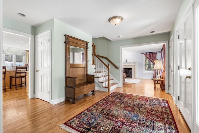 entryway featuring stairway, a tile fireplace, light wood-style flooring, and baseboards