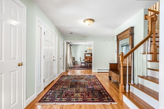 interior space with a baseboard heating unit, stairway, wood finished floors, and a chandelier