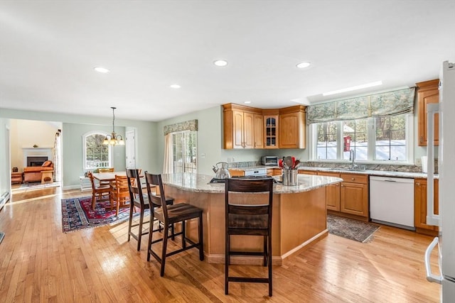 kitchen with a breakfast bar area, light wood-style flooring, recessed lighting, light stone countertops, and dishwasher