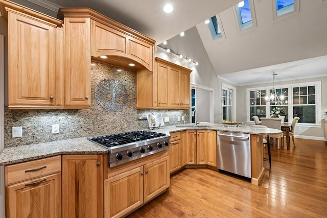 32 Rideout Rd, Hollis, NH 03049 - kitchen with stainless steel appliances, a peninsula, a chandelier, light stone counters, and light wood finished floors