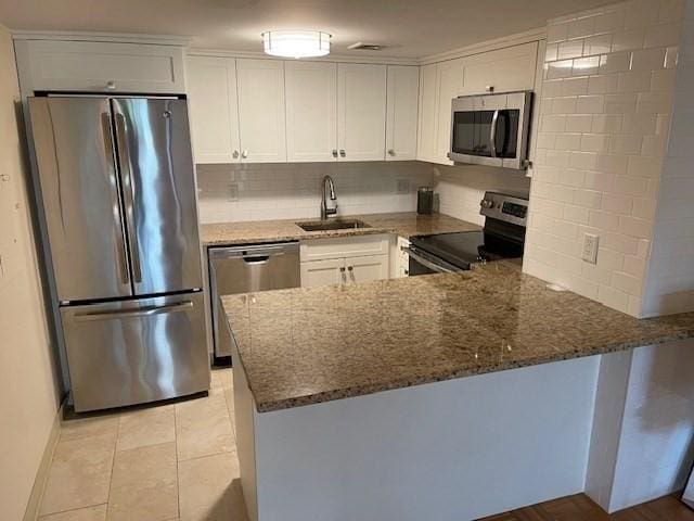 kitchen with sink, stainless steel appliances, dark stone countertops, and kitchen peninsula