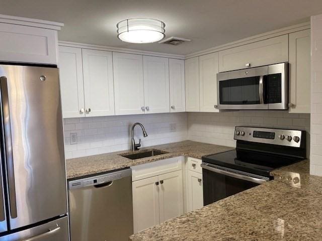 kitchen featuring light stone countertops, sink, white cabinets, and stainless steel appliances