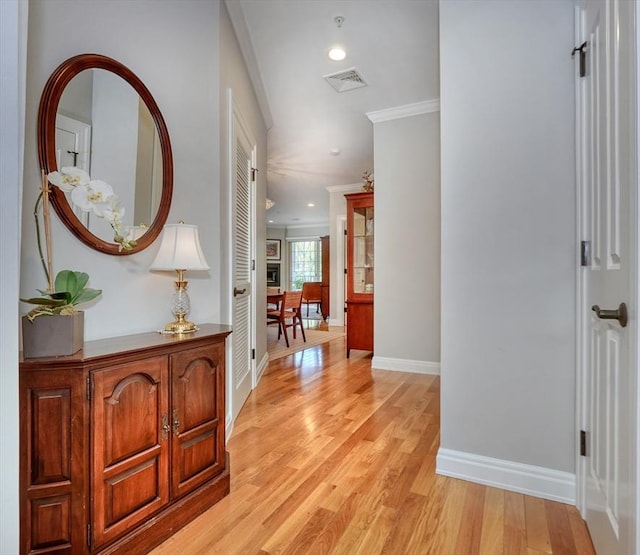 hallway featuring visible vents, ornamental molding, baseboards, recessed lighting, and light wood finished floors