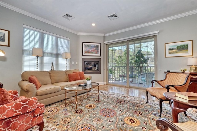 living area with baseboards, visible vents, ornamental molding, and wood finished floors