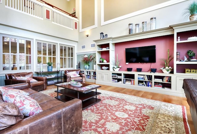 living room featuring a high ceiling, visible vents, and wood finished floors