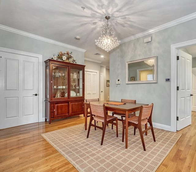 dining space featuring an inviting chandelier, light wood finished floors, crown molding, and baseboards