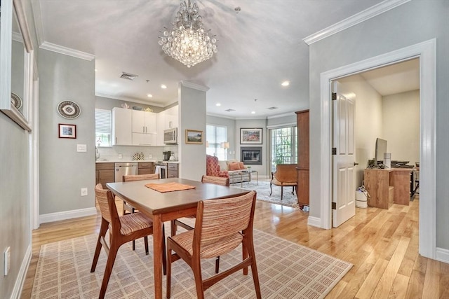 dining area with ornamental molding, light wood-type flooring, visible vents, and a notable chandelier