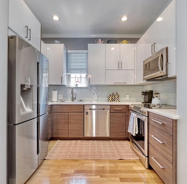 kitchen featuring ornamental molding, light countertops, brown cabinets, a sink, and appliances with stainless steel finishes