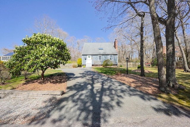 cape cod-style house featuring driveway and a chimney