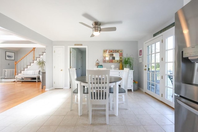 dining space featuring a ceiling fan, stairway, light tile patterned flooring, and baseboards