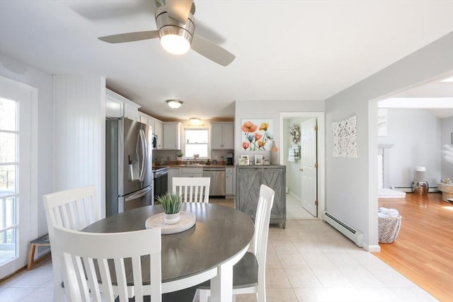 dining room featuring a baseboard radiator, a ceiling fan, and light tile patterned floors