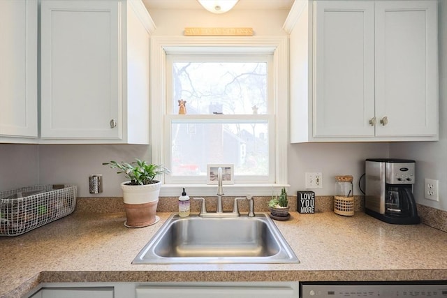 kitchen featuring a sink, dishwasher, plenty of natural light, and white cabinets
