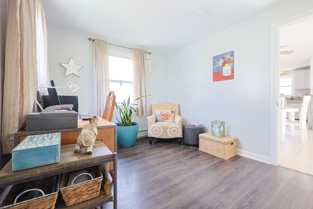 sitting room featuring wood finished floors, baseboard heating, an office area, and baseboards