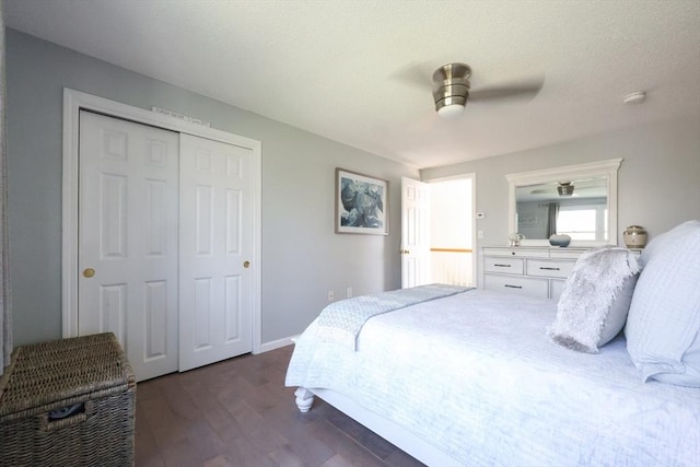 bedroom featuring dark wood-style flooring, a closet, a ceiling fan, and baseboards