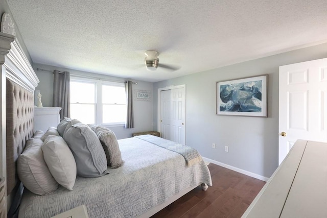 bedroom featuring dark wood-style floors, a textured ceiling, baseboards, a ceiling fan, and a closet