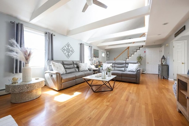 living room with stairway, healthy amount of natural light, ceiling fan, light wood-style flooring, and beamed ceiling