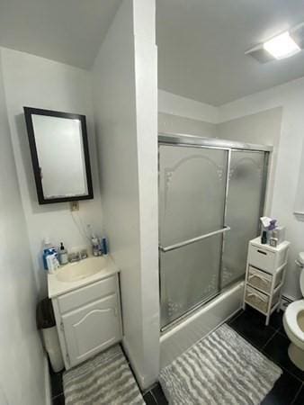 bathroom featuring an enclosed shower, toilet, vanity, and tile patterned flooring