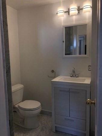 bathroom featuring toilet, vanity, and baseboards