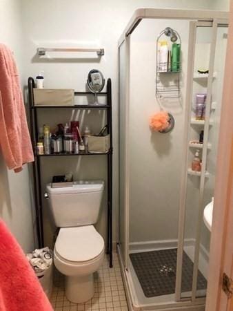 full bathroom featuring a stall shower, toilet, and tile patterned flooring
