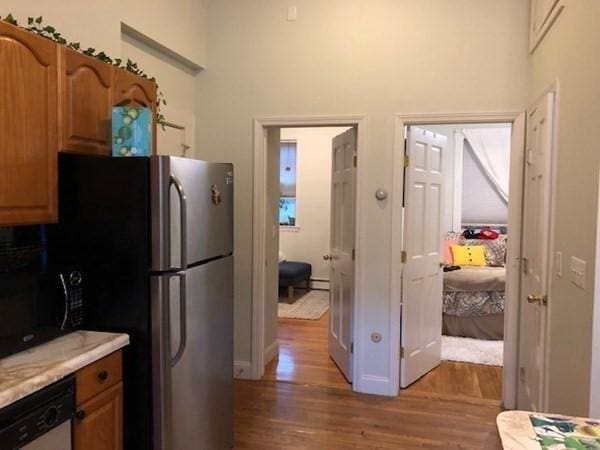 kitchen with wood finished floors, dishwasher, black microwave, a towering ceiling, and light countertops