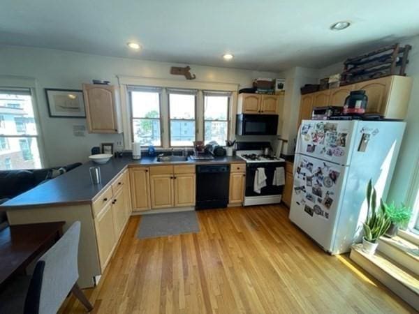 kitchen featuring black appliances, a sink, light wood-type flooring, plenty of natural light, and recessed lighting