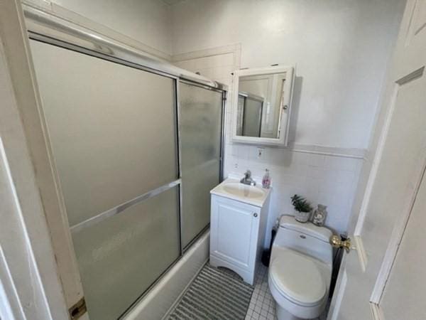 full bathroom featuring toilet, vanity, tile patterned floors, and shower / bath combination with glass door
